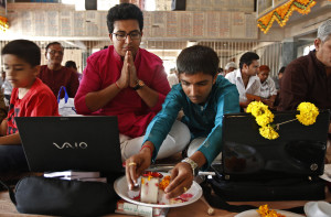 Businessmen offer prayers to Hindu gods in front of their laptops as part of a ritual to worship the Hindu deity of wealth Goddess Lakshmi on Diwali, in Ahmedabad