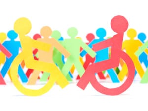 Two paper men on wheelchair. Multicolor paper crew on the background.